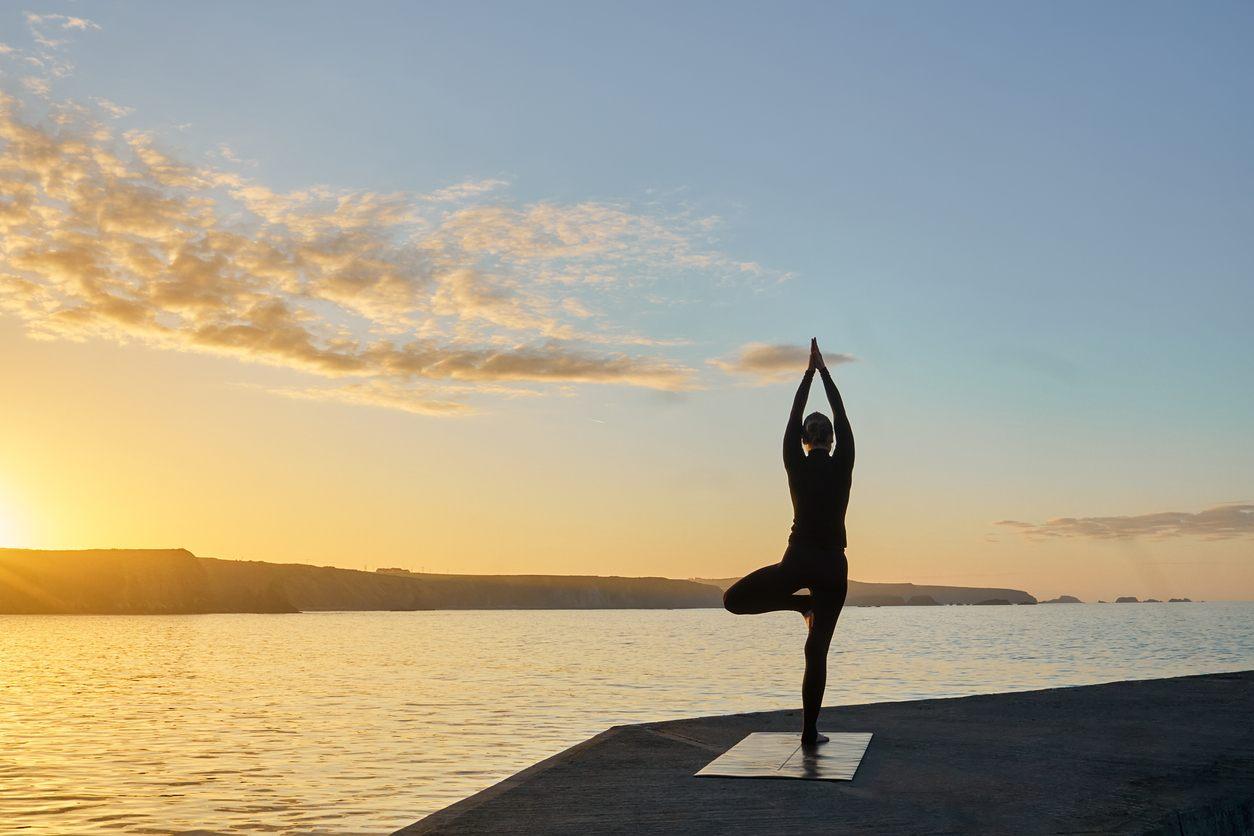 woman doing yoga in front of ocean