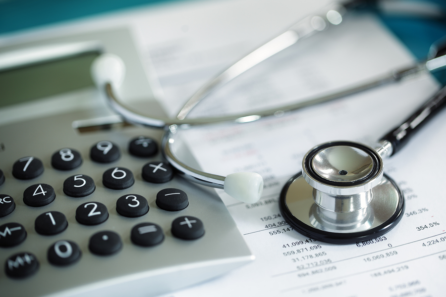 Getting help with medical financing Closeup image of stethoscope with calculator and financial documents.