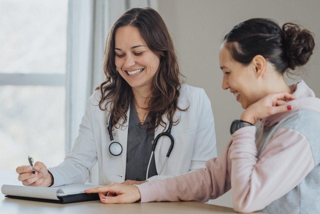 Cheerful doctor reviewing papers with female patient stock photo