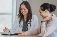 Cheerful doctor reviewing papers with female patient stock photo