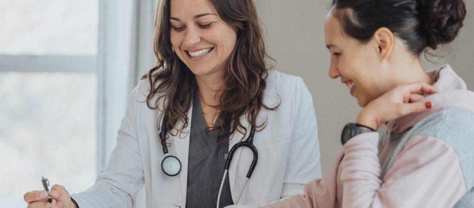 Cheerful doctor reviewing papers with female patient stock photo