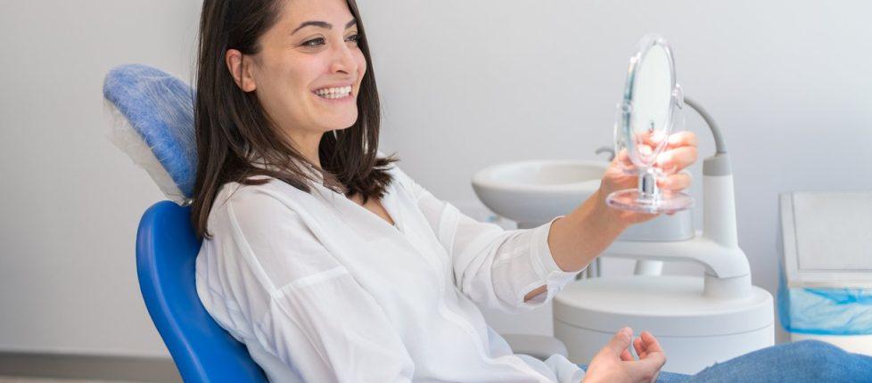 Young Woman Looking At Mirror With Smile In Dentist’s Office stock photo