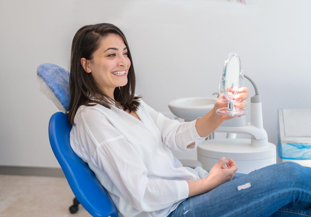 Young Woman Looking At Mirror With Smile In Dentist’s Office stock photo