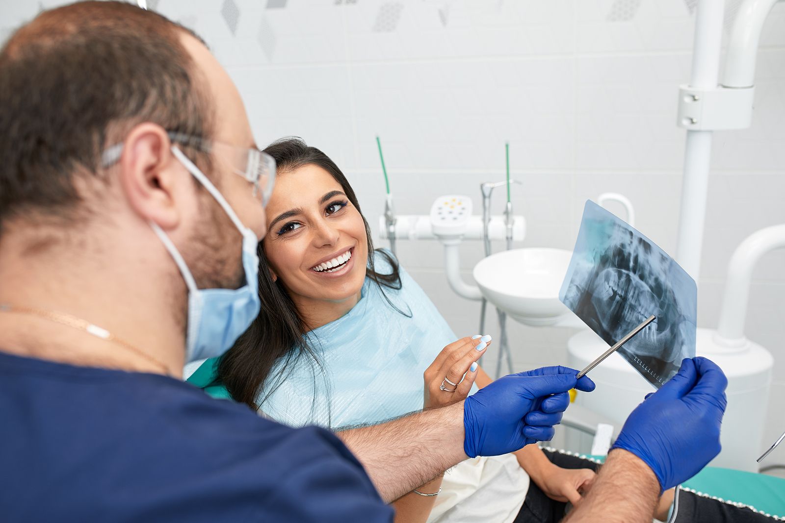 Male dentist reviewing dental extray with female patient.