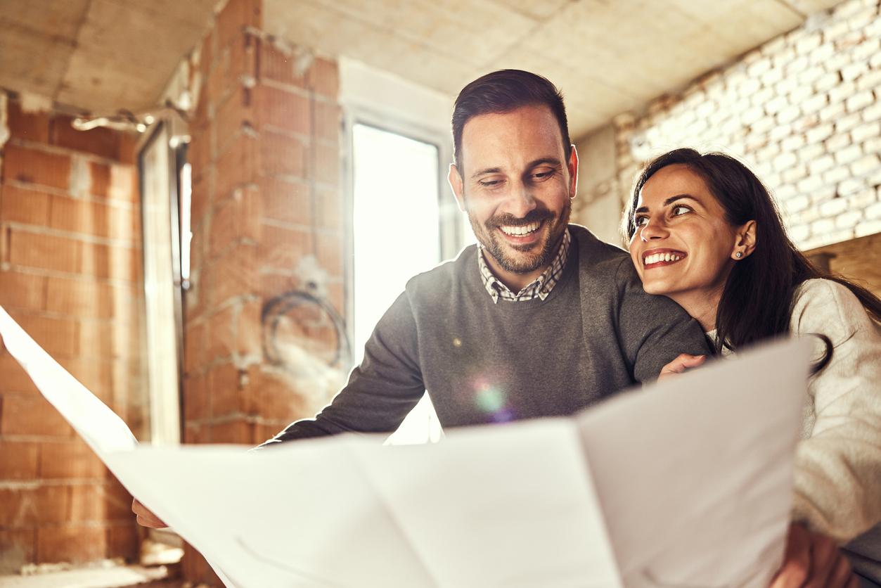 Young happy couple examining blueprints during home renovation process in the apartment.